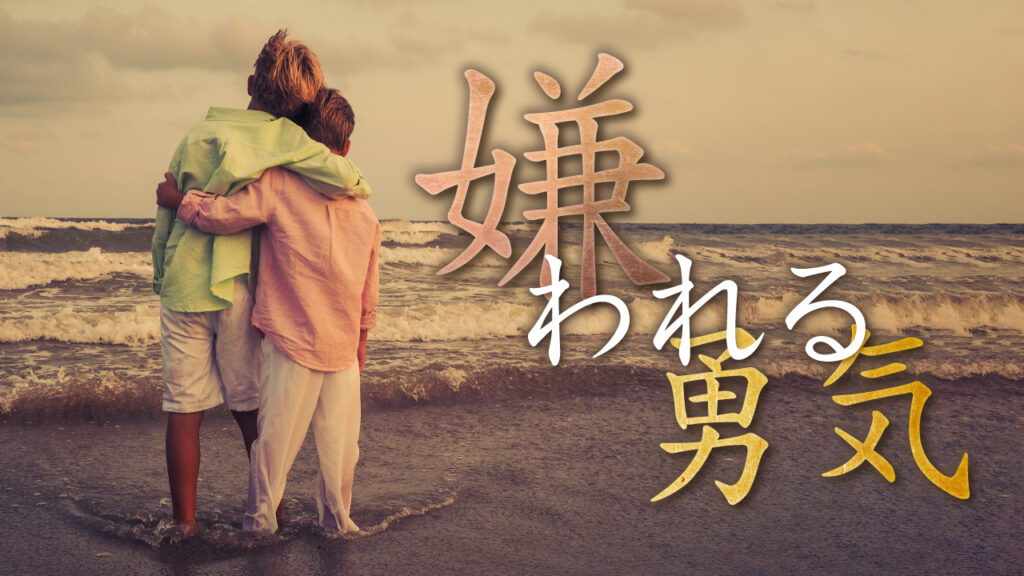 海辺で肩を組み、荒れる海を見つめる二人の少年の後ろ姿の写真に、『嫌われる勇気』という文字を重ねた作例。（デザイナーおもち制作）